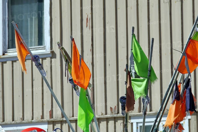 Colourful flags flutter on long poles in front of a building window, fishing, Bleik, Andøya, Nordland, Norway