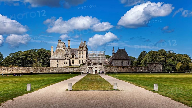 A well-preserved castle with clear skies with white clouds, surrounded by lawn, Château de Kerjean Castle in Brittany