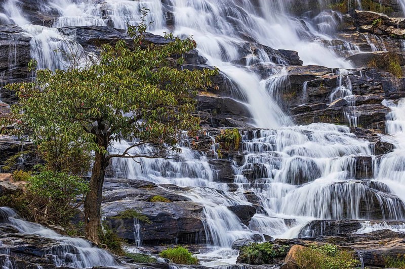 Mae Ya waterfall with cascading flowing water surrounded by lush tropical vegetation, near Doi Inthanon National Park, Chiang Mai Province, Thailand