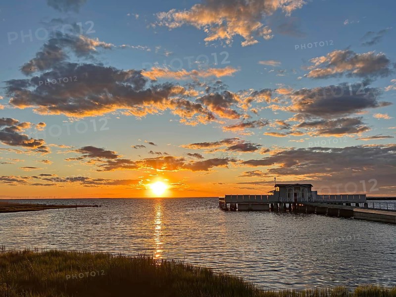 Colourful sunset at sea with jetty and dramatically illuminated clouds, Borgholm, Öland, Sweden