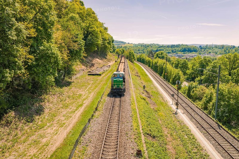 A train moves through a green landscape under a bright blue sky, electrification of the Hochrheinbahn, conversion of the railway station, Waldshut, Tiengen, Germany