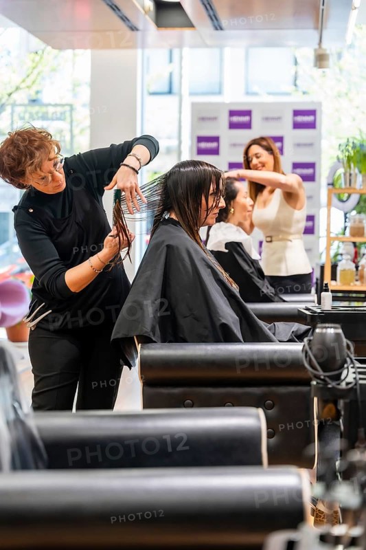 Professional hairstylists providing hair care services to female clients, cutting and styling hair in a bustling and contemporary beauty parlor environment