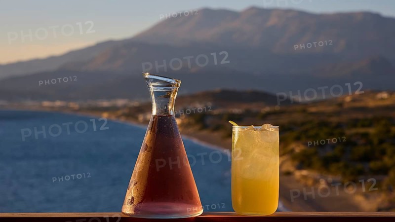 Two drinks on a railing with a view of sea and mountains at sunset, Matala, South Coast, Crete, Greek Islands, Greece