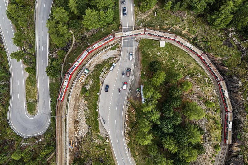 Red train of the Rhaetian railroad line, Bernina Express, 180 degree turn at the Montebello curve, aerial view, Morteratsch, Switzerland