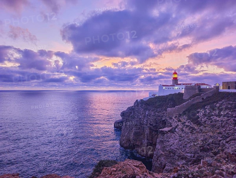 View of the Lighthouse of Cabo de Sao Vicente in Sagres, Algarve, Portugal, at dusk with rugged coastline and Atlantic ocean