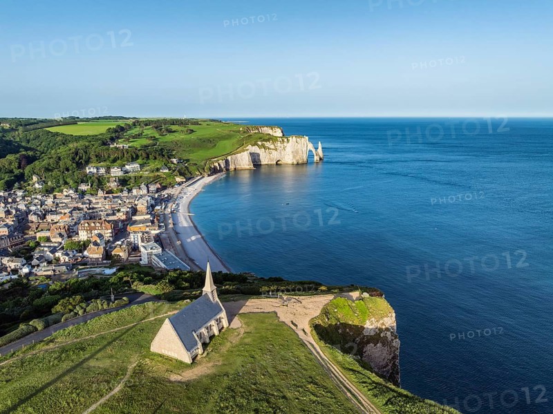 Aerial view of the Notre Dame de la Garde chapel after sunrise at the Falaise d'Amont viewpoint, on the right the coastal town of Étretat with the beach, on the horizon the Porte d'Aval rock formation, Étretat, Alabaster Coast, La Côte d'Albâtre, chalk cliffs, English Channel, Seine-Maritime, Normandy, France