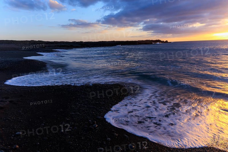 Lanzarote, Canary Islands, Spain, Europe, Los Hervideros, waves gently wash the beach at sunset, the sky turns blue and orange
