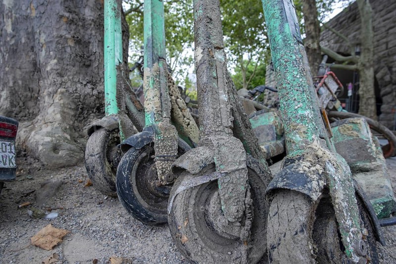 Heavily silted e-bikes and e-scooters recovered from the Rhine show the consequences of improper disposal and the impact on the environment and water, the recovered vehicles were secured on the shore and prepared for proper disposal, Cologne, North Rhine-Westphalia, Germany