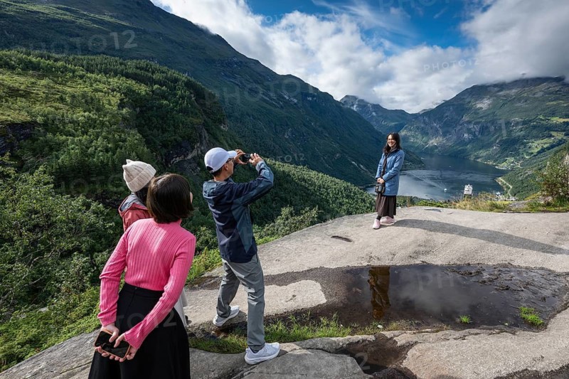 Asian tourists take a souvenir photo, Geiranger, UNESCO World Heritage Site Geiranger Fjord, Stranda Municipality, Møre og Romsdal, Norway