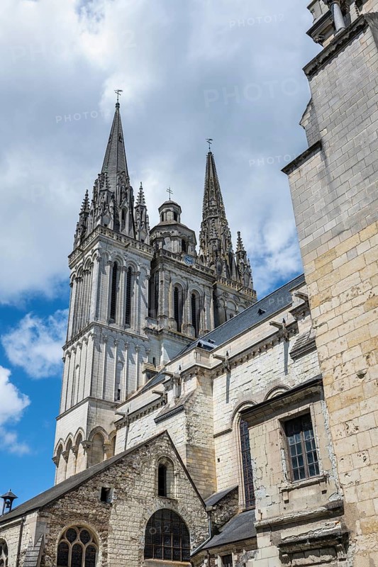 Historic west façade of the Gothic Saint-Maurice cathedral photographed in steep perspective from bottom to top, with the filigree stone carvings and sculptures clearly standing out in sunlight, Place Sainte-Croix, Angers, Maine-et-Loire, Pays de la Loire, France