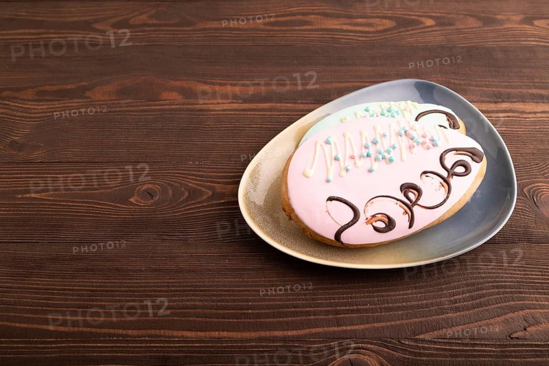 Glazed pink and blue decorated cookies, on brown wooden background, copy space, side view