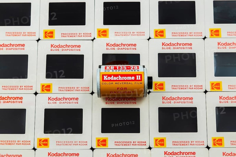Old roll of 1970s 35mm Kodachrome II color reversal slide film for daylight shooting on top of arranged rows of 35mm Kodak Kodachrome slides mounted in white cardboard frames with bilingual English and French wording for Canadian market, Studio Composition, Quebec, Canada