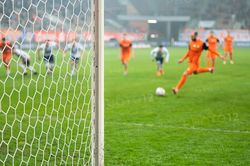 Detail of goal's post with net and football player during penalty kick in the background in Lubin, Poland