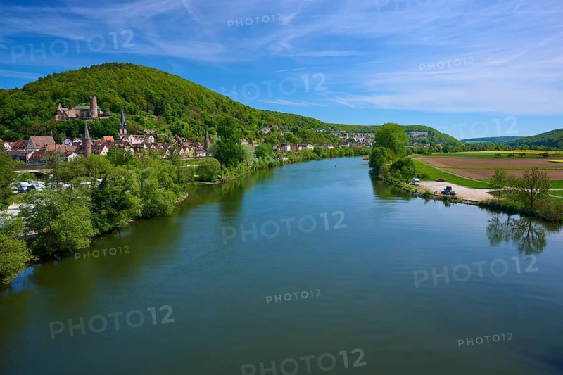 Picturesque river landscape with a village on the banks, surrounded by green hills and under a blue sky, Main, Gemünden am Main, Main-Spessart district, Mainfranken, Lower Franconia, Bavaria, Germany