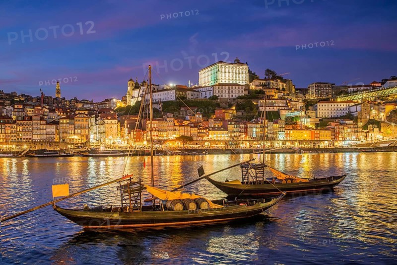 Blue hour night scene of Porto rabelo boats on Douro River by Ribeira, Portugal, with evening lights and moored boats on the waterfront, quayside view