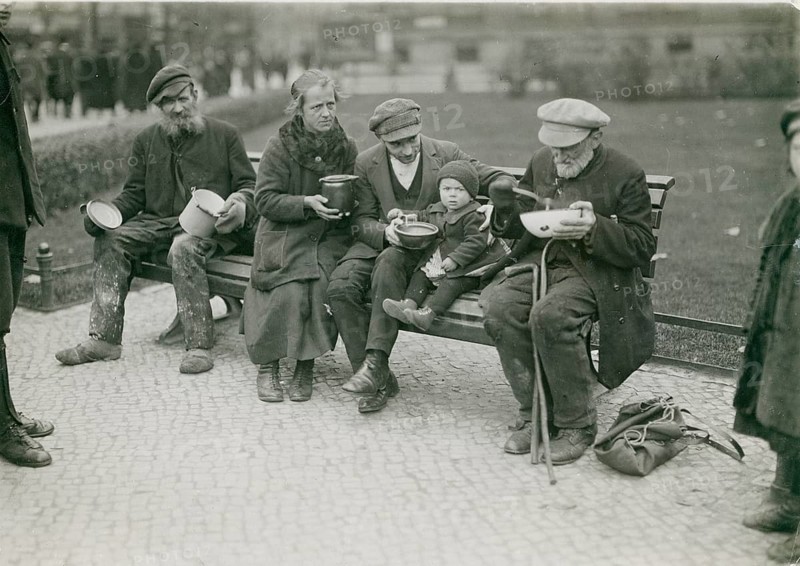 Berlin, unemployed people, beggars, soups, poverty, hunger, group of people sitting on a bench holding simple bowls in their hands, Weimar Republic, 1919
