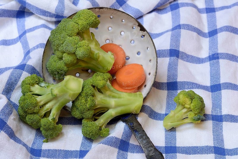 Broccoli in sieve trowel and carrot slices, Brassica oleracea var. italica