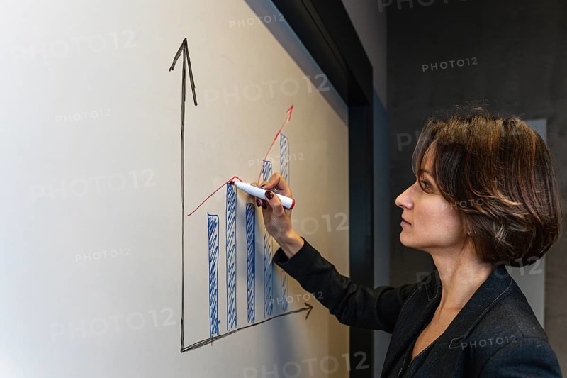 Professional businesswoman drawing growth chart on whiteboard during presentation
