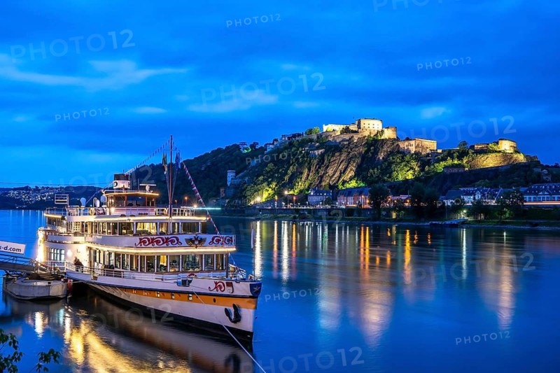 The Ehrenbreitstein Fortress, on the right side of the Rhine, opposite the Deutsches Eck, evening lighting, sightseeing boat on the left bank, Koblenz, Rhineland-Palatinate, Germany