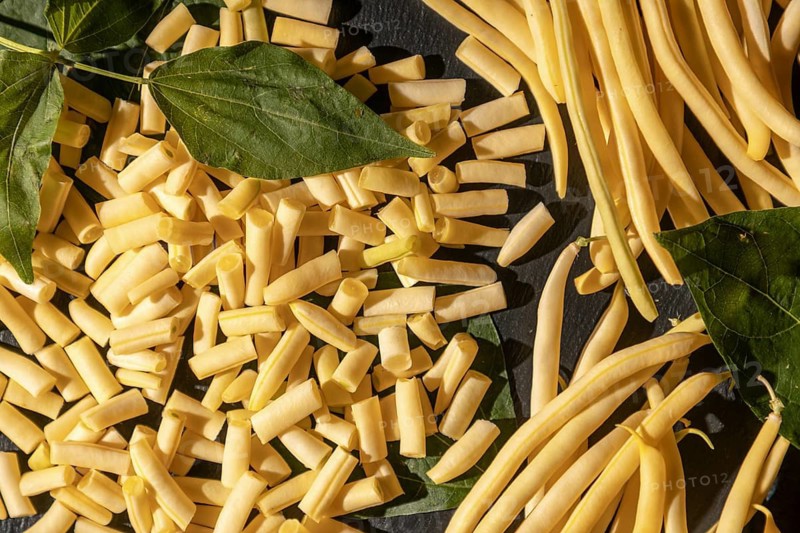 Fresh yellow beans with sliced pieces on a dark background