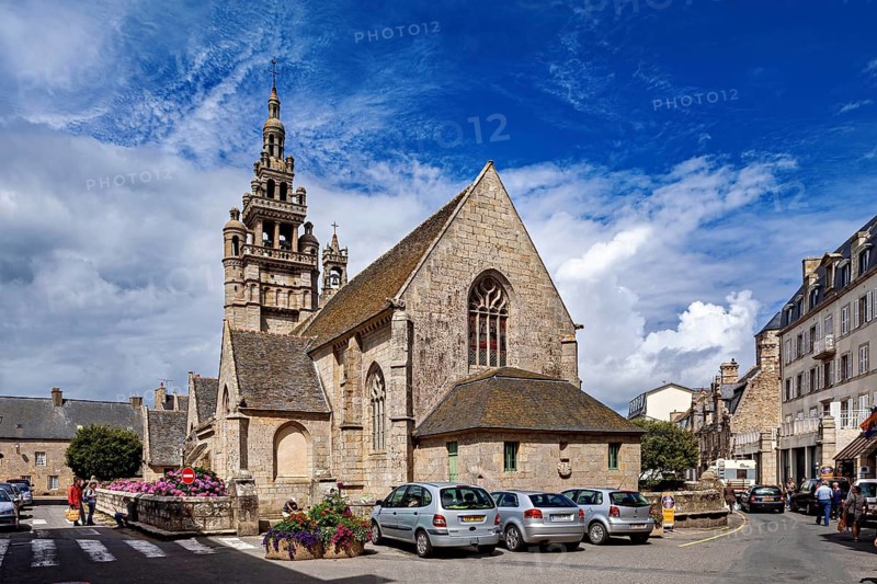 Historic church in an old town with cars in the foreground and blooming plants, The Notre-Dame-de-Croaz-Batz in Roscoff in Brittany