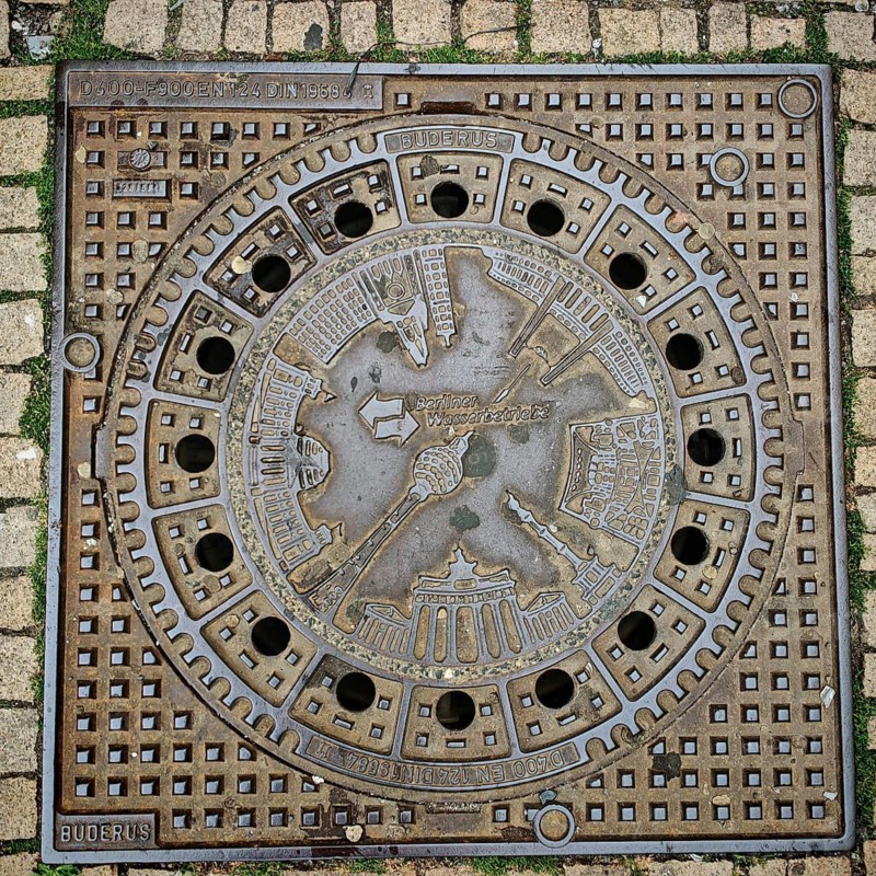 Artistically designed Berlin manhole cover with reliefs and city motifs, Alexanderplatz, Berlin