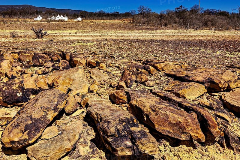 Massive rock formations on dry soil with sparse vegetation under clear skies, the thornshrub savanna in the Caatinga countryside in the federal states of Pernambuco and Bahia in Brazil