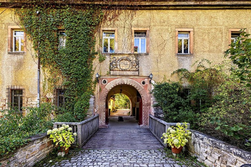 A historic entrance gate with bridge and blooming plants, Tonndorf Castle in the Weimar region in Thuringia