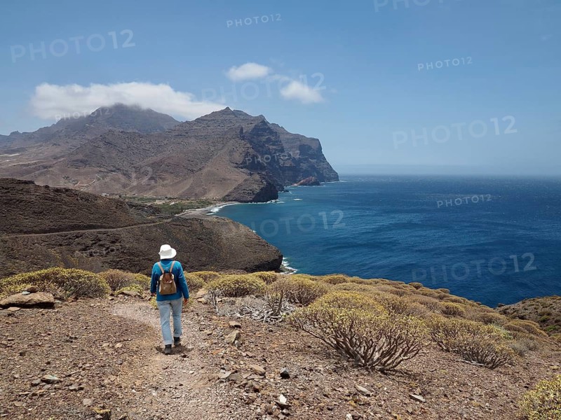 Female hiker on a rocky path with views of the coast and the sea, La Aldea de San Nicolas, Gran Canaria, Spain