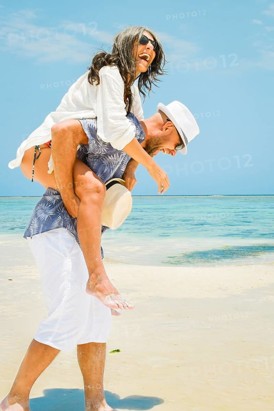 Beautiful traveler tourist happy couple walks piggyback in tropical beach in Maldives island. Romantic holidays vacation