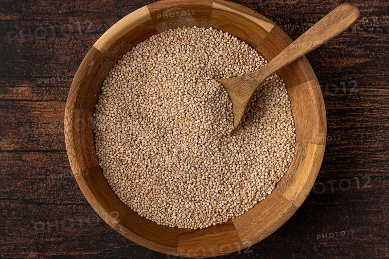 Quinoa in a wooden bowl with a spoon on a dark wooden table