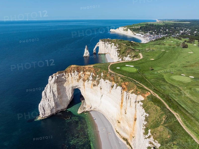 Aerial view of the La Manneporte rock gate in the evening sun, behind it the Porte d'Aval rock formation with the free-standing rock pin Aiguille d'Étretat, well-known sights and natural beauty on the chalk coast with the distinctive rock pin, behind it the holiday resort of Étretat with the swimming beach, on the horizon the Falaise d'Amont cliffs, right on the cliffs of the Golf d'Étretat golf course, founded in 1908, Alabaster Coast, La Côte d'Albâtre, Chalk Cliffs, English Channel, Seine-Maritime, Normandy, France