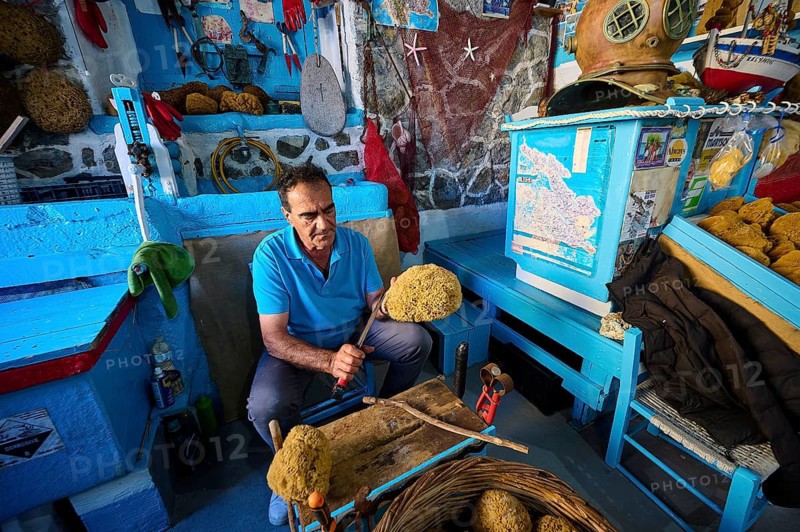 A man works on a sponge in a blue workshop with traditional tools, sponge moufactory, Nikolas Gourlas, Pothia, main town, port, Kalymnos, Sponge Diving Island, Dodecanese, Greek Islands, Greece