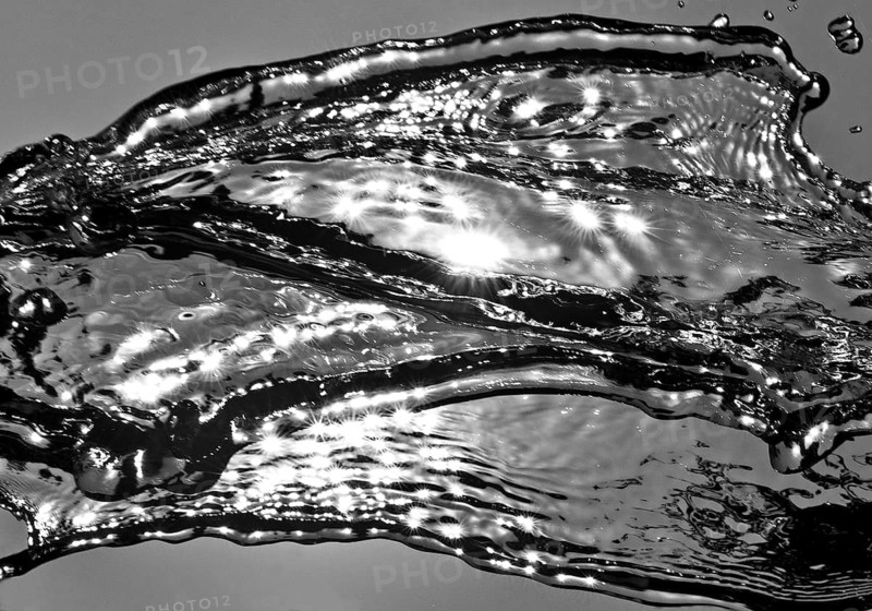 Water frozen by short exposure moving in backlight in front of the sun