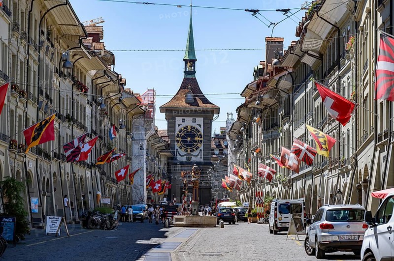 Kramgasse with historic houses decorated with cantonal flags and Swiss national flags, back clock tower Zytglogge, old town, Bern, Canton of Bern, Switzerland