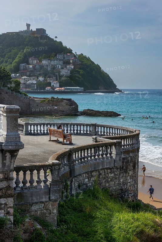 Woman sitting on a bench on the promenade at Bicentennial Balcony, La Concha beach, San Sebastián, Basque Country, Spain