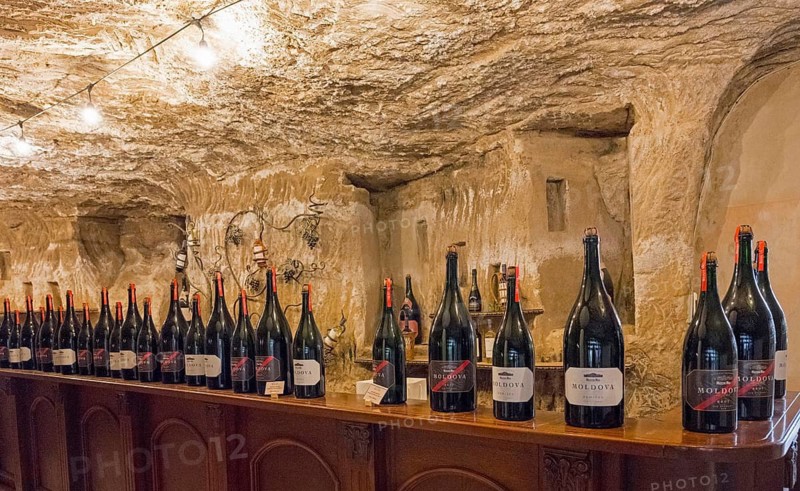 Large wine bottles stand on a long shelf in an illuminated cellar environment, sales room, Milestii Mici Winery, Mile?tii Mici, Republic of Moldova, Moldova