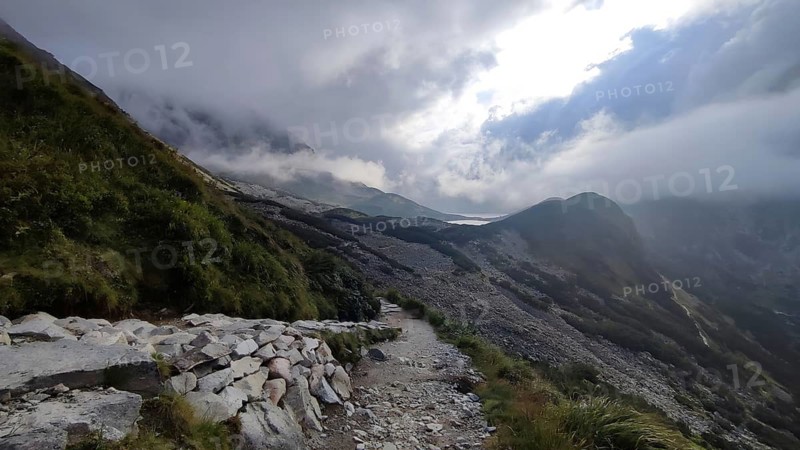 A rocky hiking trail snakes through the cloudy mountain landscape, hiking in the High Tatras National Park, Carpathian Mountains, Poland