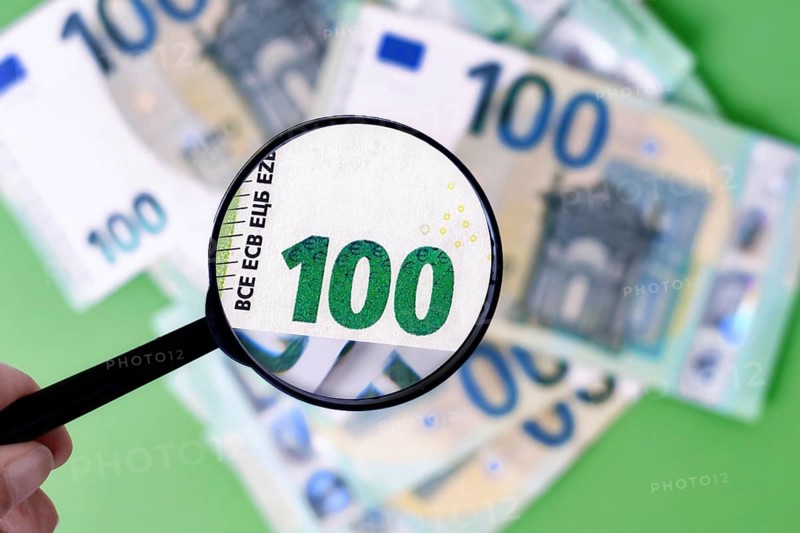 Magnifying glass checking authenticity of euro banknote
