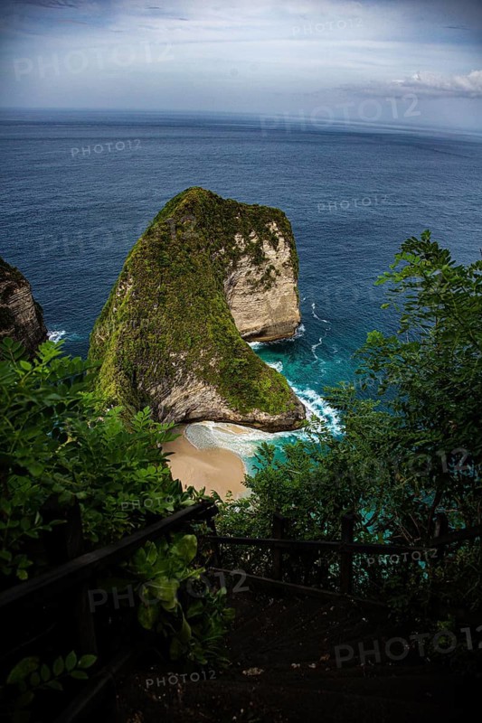 An impressive coastal cliff with lush vegetation and calm, turquoise waters, looking down from above onto the famous, deserted white sandy beach of Kelingking (T Rex Beach), Nusa Penida Island, Klungkung Regency, Bali, Indonesia, South-East Asia