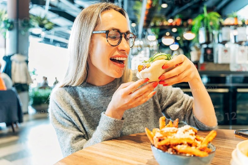 Woman Laughing While Enjoying a Steamed Bao Bun with Crispy Filling