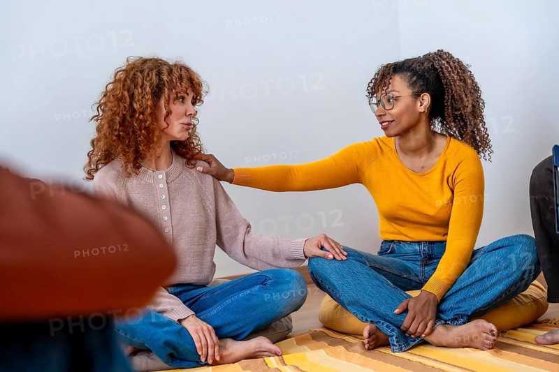 Diverse women connecting and offering comfort and understanding to each other, creating a safe and supportive environment for open discussion during a mental health counseling session