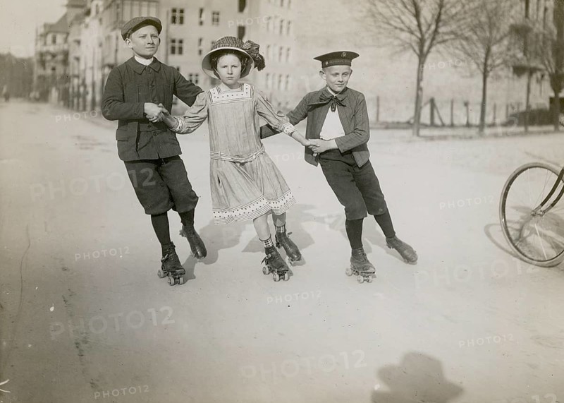 Berlin, ice-skating, middle class, children, street, practice, help, free time, three children in historical clothing, playing on roller skates on a street, Philipp Kester, around 1906