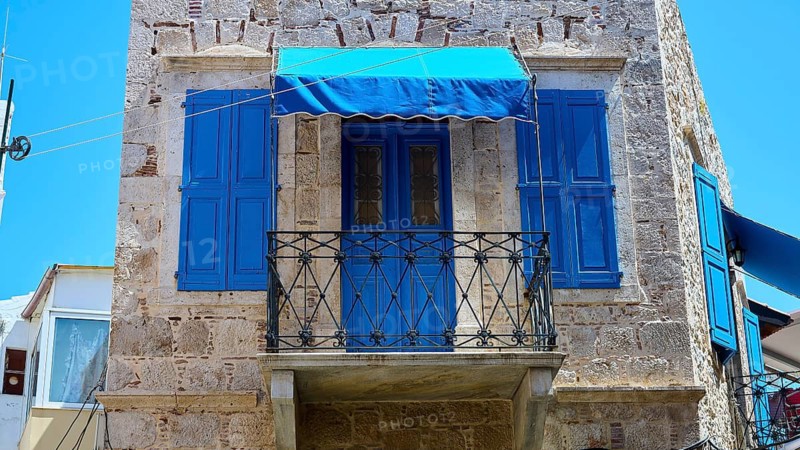 Rustic stone building with blue shutters and balcony in a Mediterranean setting, Pothia, main town, port, Kalymnos, Sponge Diving Island, Dodecanese, Greek Islands, Greece