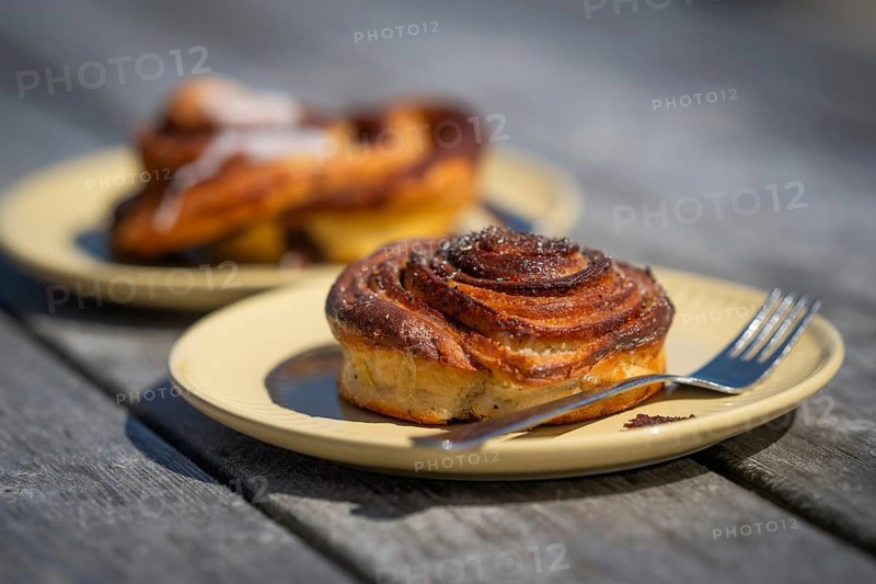 Cinnamon roll and fork lie on a light yellow plate, Houvig, Ringkøbing Fjord, Denmark