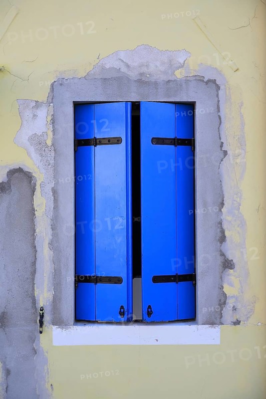 Modern window with blue shutters on yellow wall, renovated impression through distinctive colors, windows with blue shutters, colorful houses on the island of Burano, Venice, Veneto, Italy