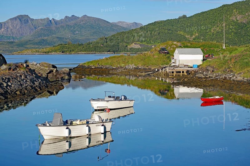White boats are lying on a quiet lake with mountain reflections under a clear sky, Hamn, Senja, Troms, Norway
