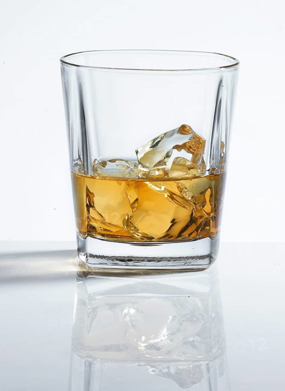 Whisky on the Rocks in a tumbler against a white background, studio shot