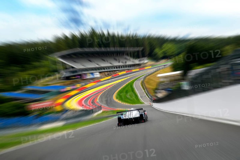 Photo with speed effect from perspective view of racing car racing car drivers for motorsport at leading race car in front of high-speed curve curve left turn with stream flowing Eau Rouge from Circuit de Spa Francorchamps Spa-Francorchamps racetrack behind it steeply rising right turn Raidillon and large stand, Stavelot, Ardennes, Walloon region Wallonia Wallonia, Belgium