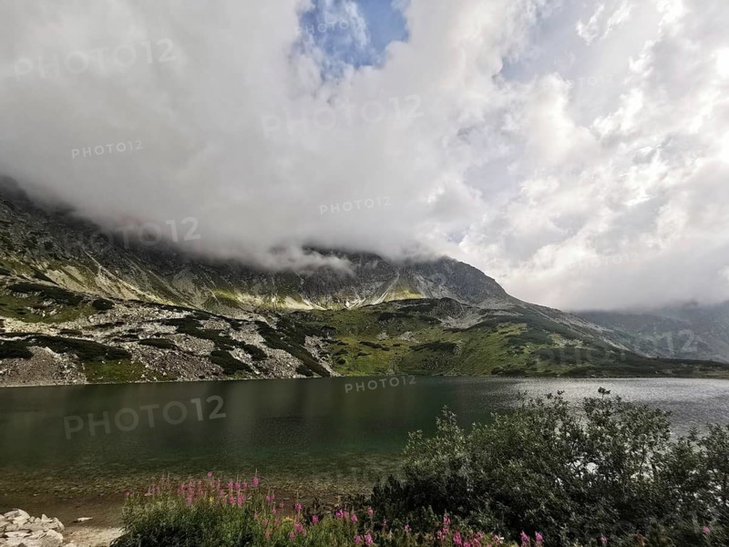 A quiet mountain lake surrounded by cloudy mountains and an impressive sky, Schronisko, High Tatras National Park, Carpathian Mountains, Poland